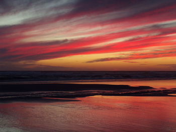 Scenic view of sea against dramatic sky during sunset