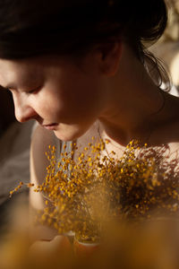 Sensual portrait of young woman looking down with mimosa flowers
