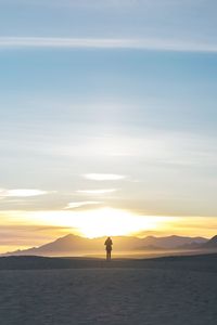 Silhouette man standing on beach against sky during sunset