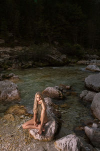 Woman relaxing on rock by river