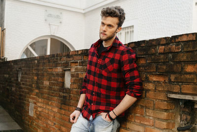 Handsome man standing against brick wall