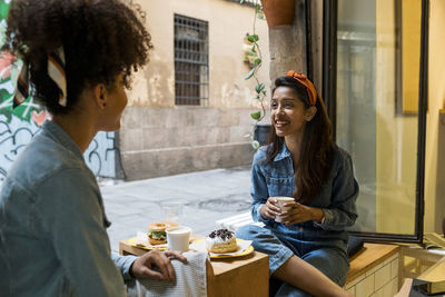 Friends smiling while having food and drink sitting at cafe