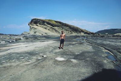 Full length of shirtless man standing on land against sky