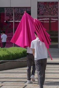 Rear view of woman with umbrella walking on street