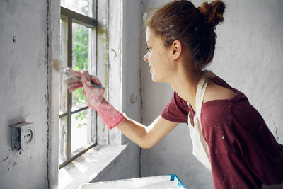 Side view of young woman looking through window