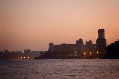 Illuminated buildings in city against sky at sunset