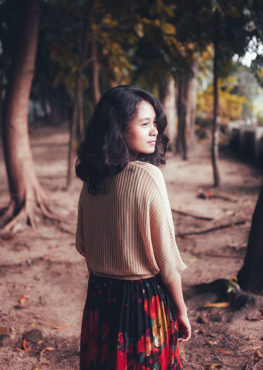 tree, one person, standing, real people, hairstyle, hair, land, leisure activity, long hair, lifestyles, nature, black hair, women, casual clothing, focus on foreground, forest, day, plant, outdoors, beautiful woman, contemplation