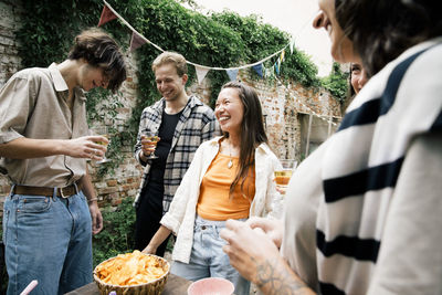 Young and happy multiracial friends enjoying during dinner party in back yard