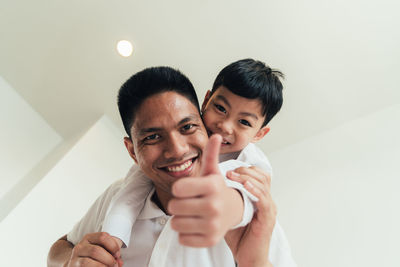 Portrait of smiling father giving piggyback to son at home