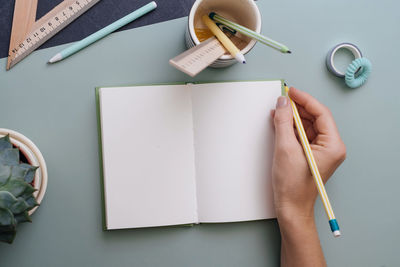 Cropped hands of woman writing on book