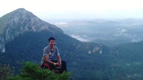 Woman sitting on mountain against sky