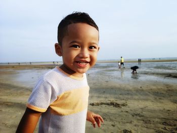 Portrait of smiling boy at beach against sky