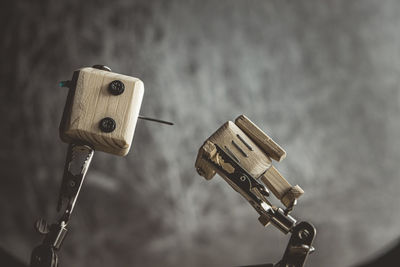 Wooden robot android stands on a table under a magnifying glass. metal clamps with magnifying glass