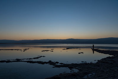 Scenic view of lake against clear sky at sunset