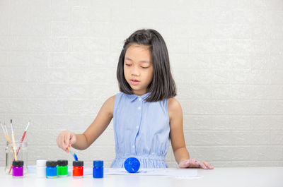 Full length of a girl looking away against wall