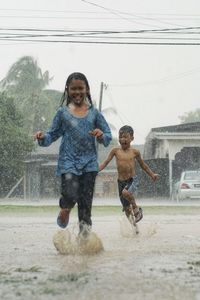 Kids playing out in the rain. children play outdoors in heavy rain. 