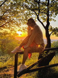 Low angle view of woman sitting on tree