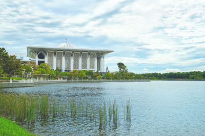 Building by lake against cloudy sky