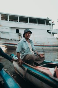 Full length of man sitting on boat at canal