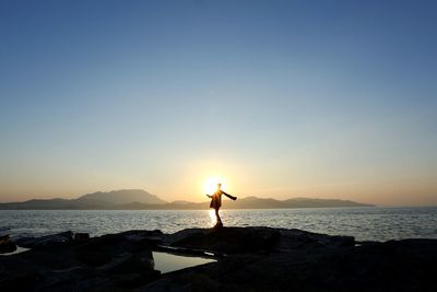 Man standing in sea against sky during sunset