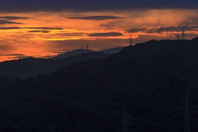 Scenic view of silhouette mountains against orange sky