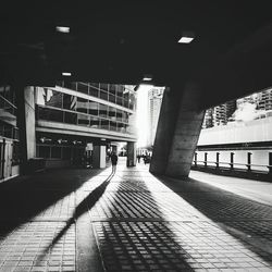 Woman figure casting long shadow in sunlit underpass