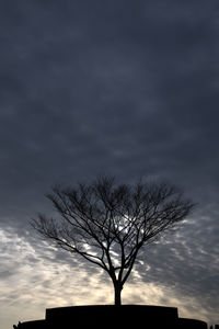 Low angle view of bare tree against cloudy sky