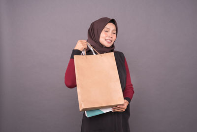 Portrait of smiling young woman standing against wall