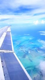 Aerial view of airplane wing over sea against sky