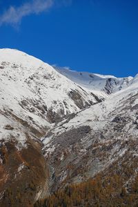 Low angle view of snow covered landscape against blue sky