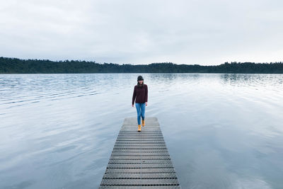 Young woman walking on jetty over lake