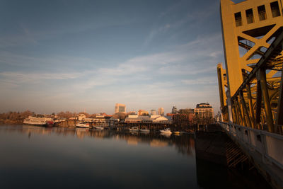 Buildings by river against sky in city