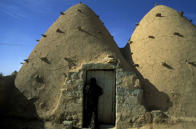 Woman entering abandoned adobe house