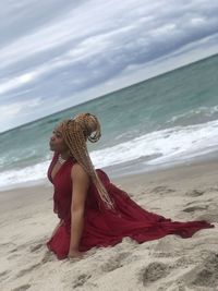 Woman with umbrella on beach against sea