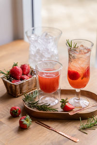 Refreshing summer drink cocktail with strawberry and ice cubes in jug and glasses infused water.