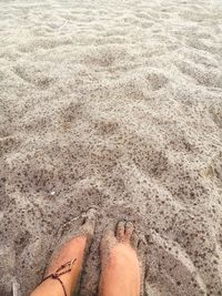 Low section of woman standing on sand during a rainy day