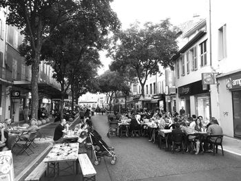 People on sidewalk cafe by street in city