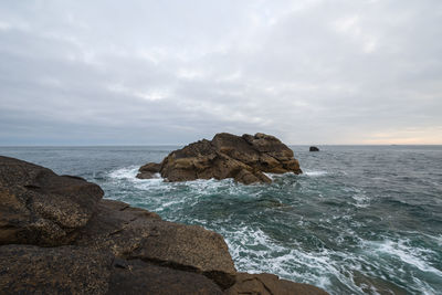 Scenic view of rocks on sea against sky