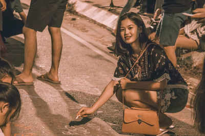 Portrait of woman writing on road in city