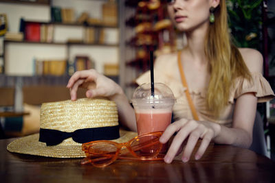 Midsection of woman holding drink in restaurant