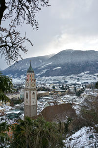 Scenic view of building and mountains against sky during winter
