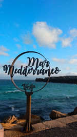 Information sign on beach against sky