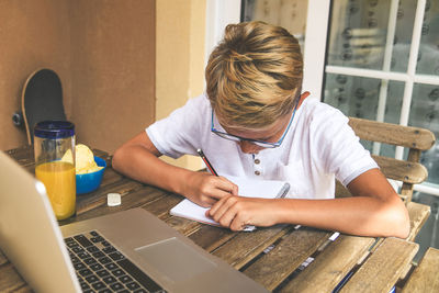 High angle view of teenager writing on diary