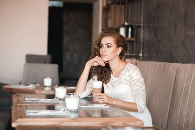 Young woman looking away while sitting at cafe