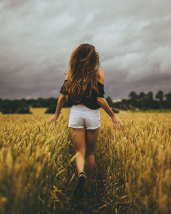 Rear view of woman standing in wheat field