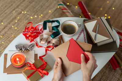 Woman hands are packing a christmas postcard and a gift card into the envelope. concept.