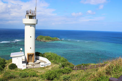 Lighthouse by sea against blue sky