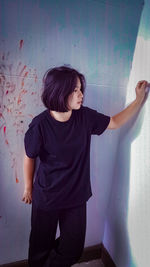 Boy standing against wall at home