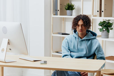 Young woman using laptop while sitting on table