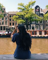 Woman standing by canal against buildings in city